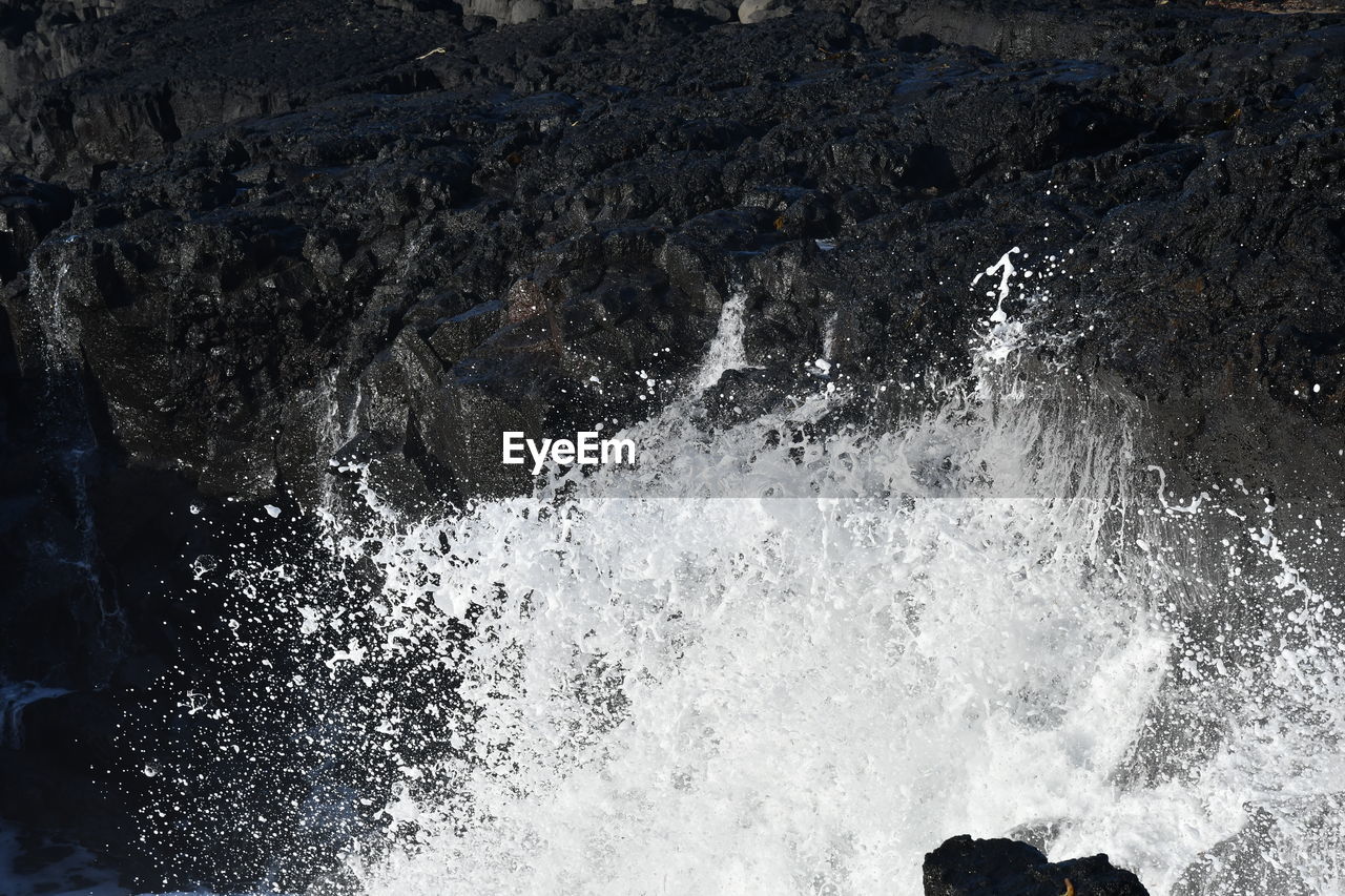 HIGH ANGLE VIEW OF WAVES SPLASHING ON ROCKS