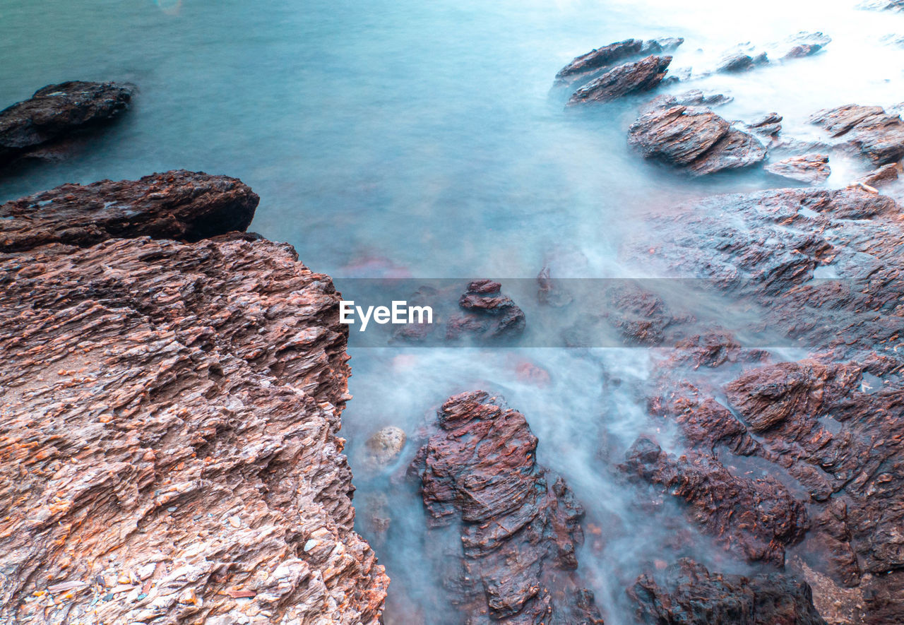 Long exposure of sea with smooth wave and rock landscape.