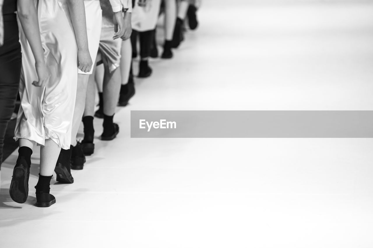 Low section of fashion models walking on runway