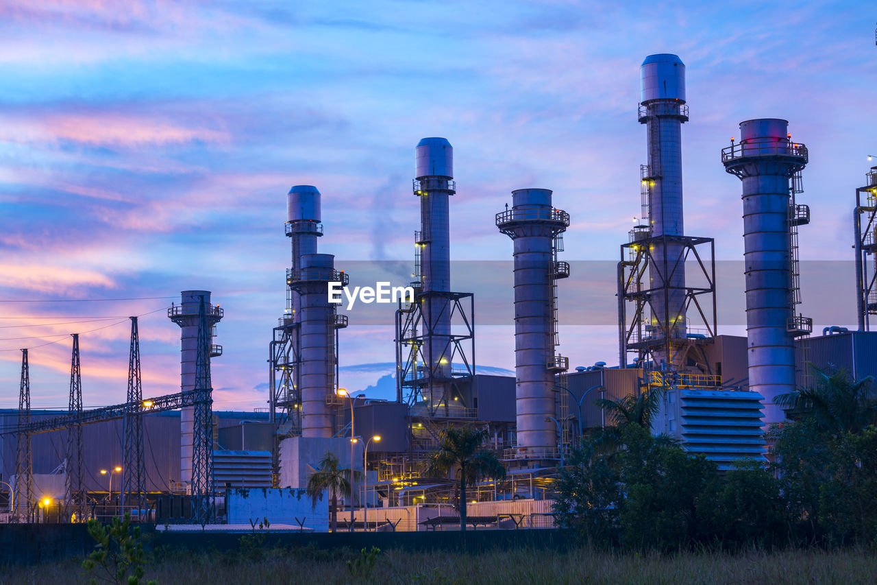 LOW ANGLE VIEW OF ILLUMINATED FACTORY AGAINST SKY