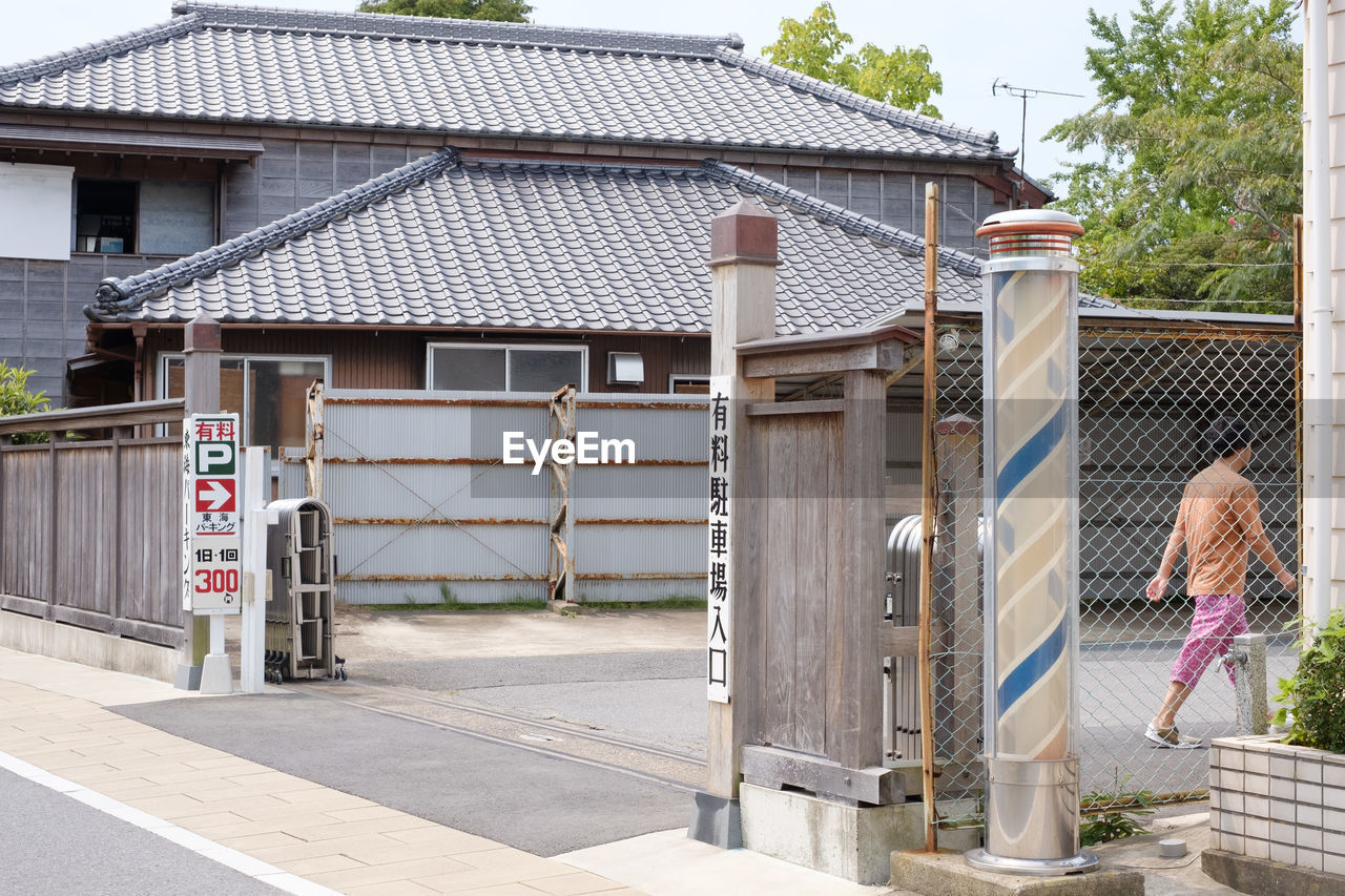 REAR VIEW OF MAN OUTSIDE HOUSE AGAINST BUILDINGS