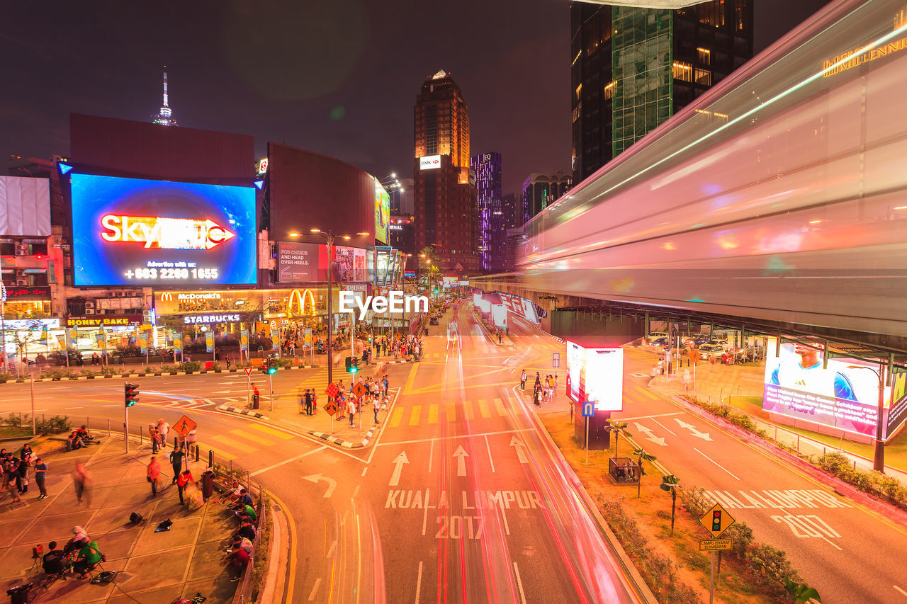 Light trails on road amidst buildings in city at night