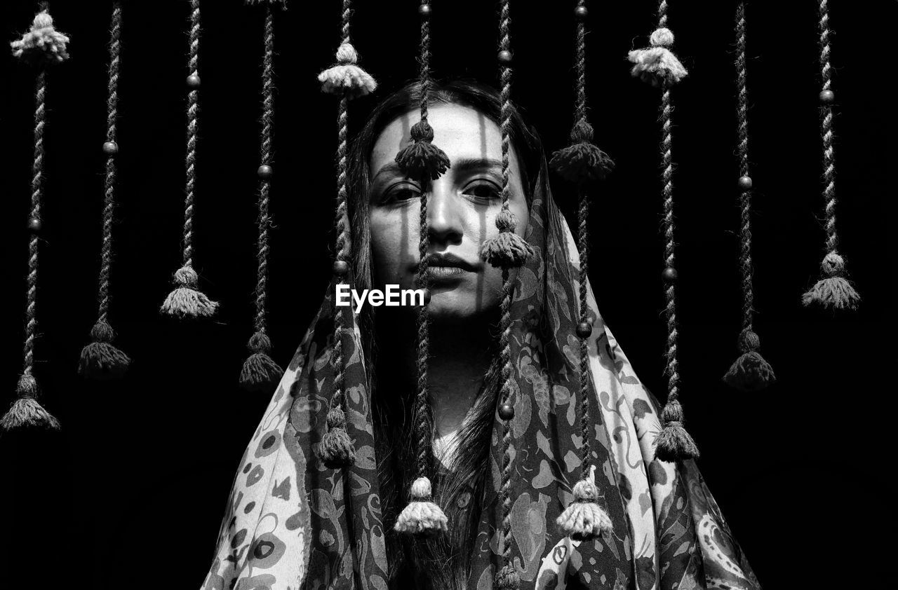 Portrait of woman by wind chime against black background