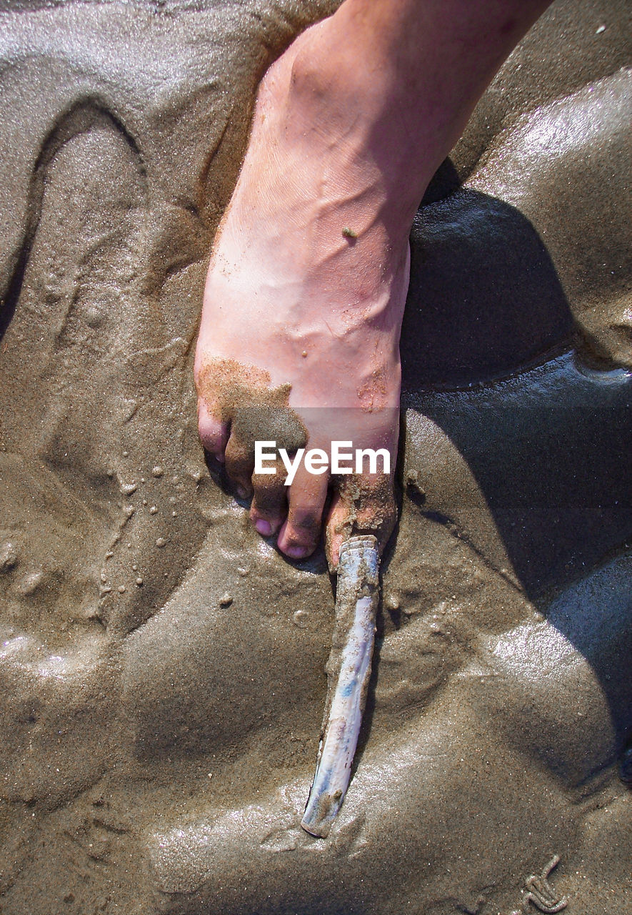 CLOSE-UP OF MAN HOLDING HANDS ON SAND