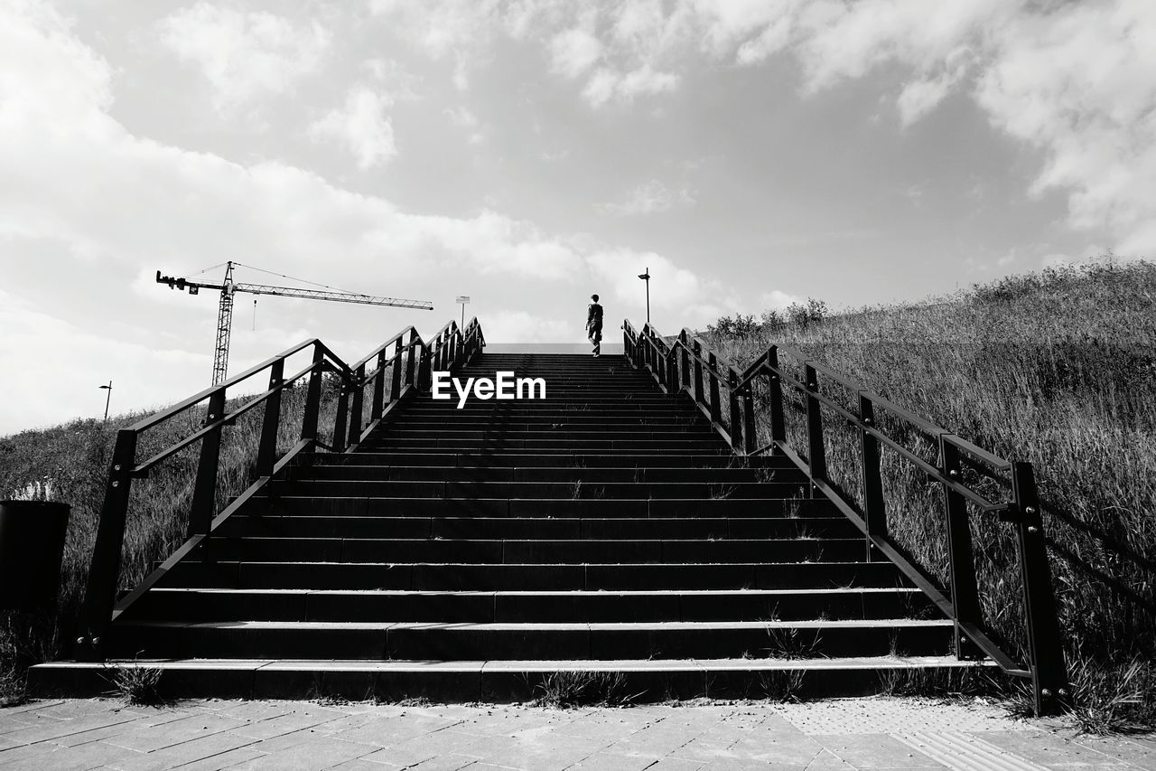 Low angle view of person on steps against sky