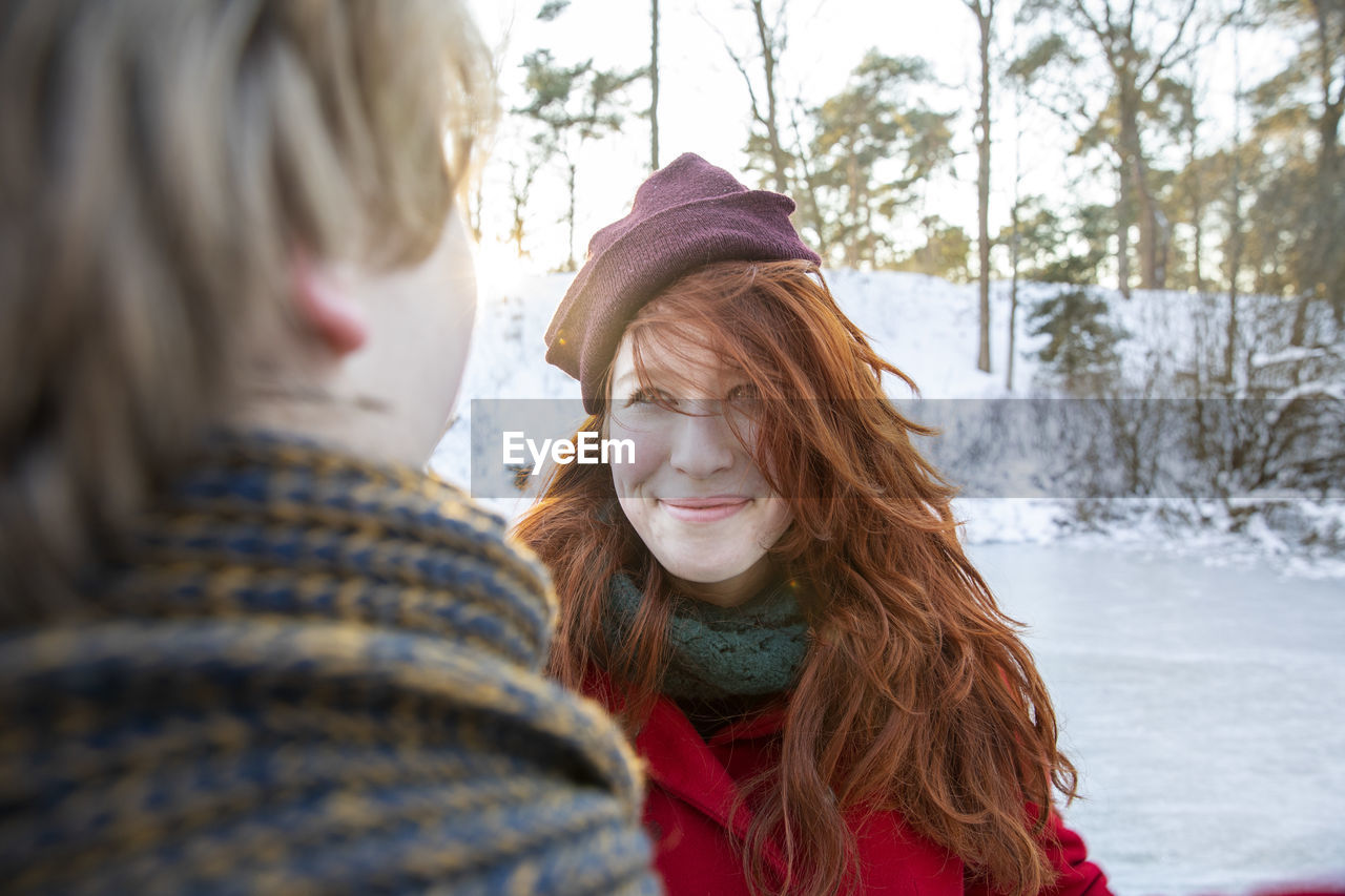 Smiling redhead woman wearing knit hat looking at boyfriend