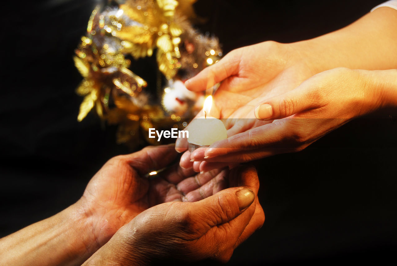 CLOSE-UP OF HANDS HOLDING ILLUMINATED LIGHT