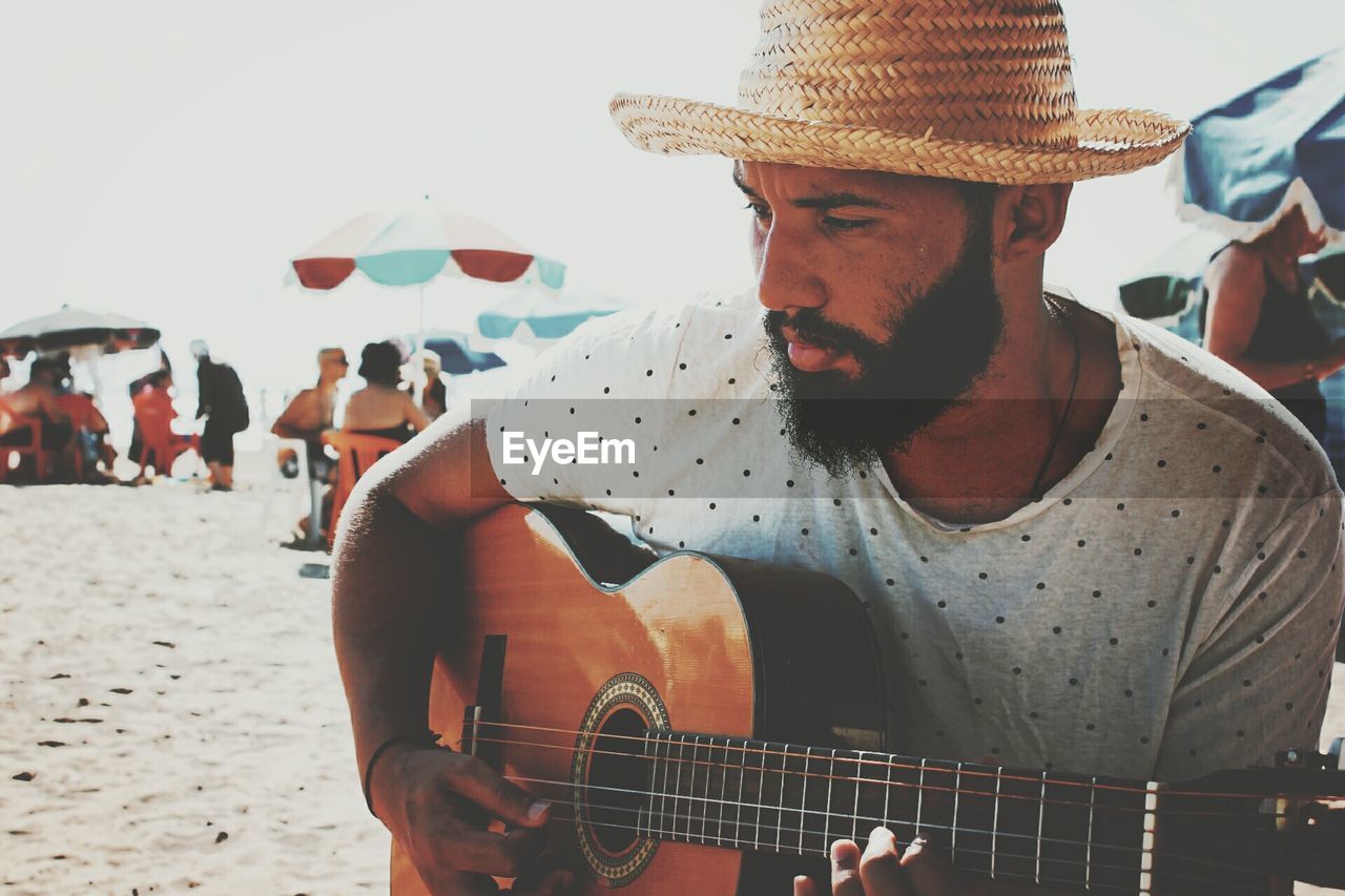 Close-up of man playing guitar at beach