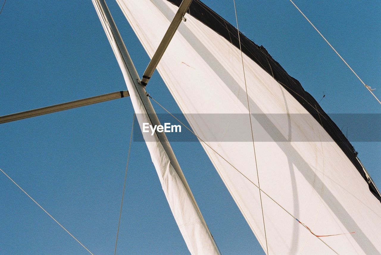 Low angle view of sailboat against clear blue sky