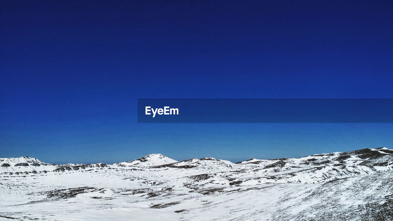 LOW ANGLE VIEW OF SNOWCAPPED MOUNTAINS AGAINST BLUE SKY