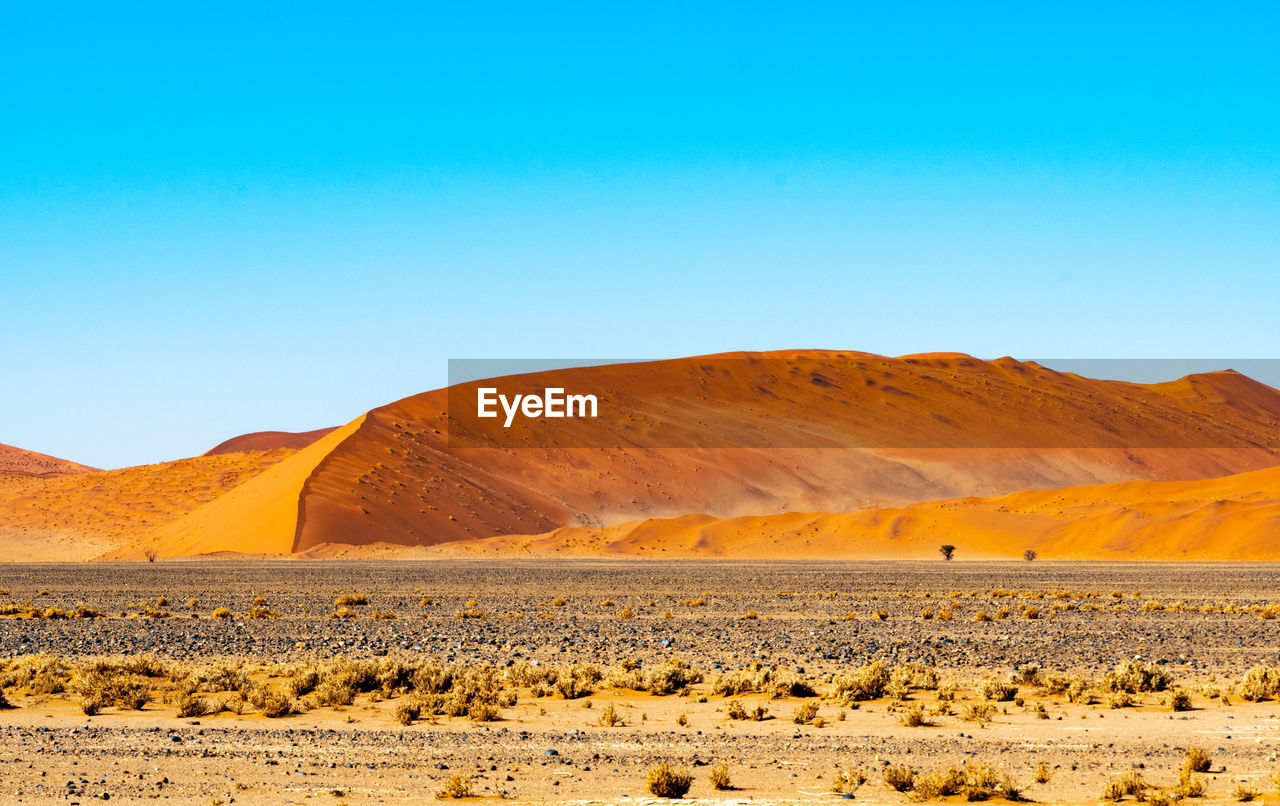 Scenic view of desert against clear blue sky