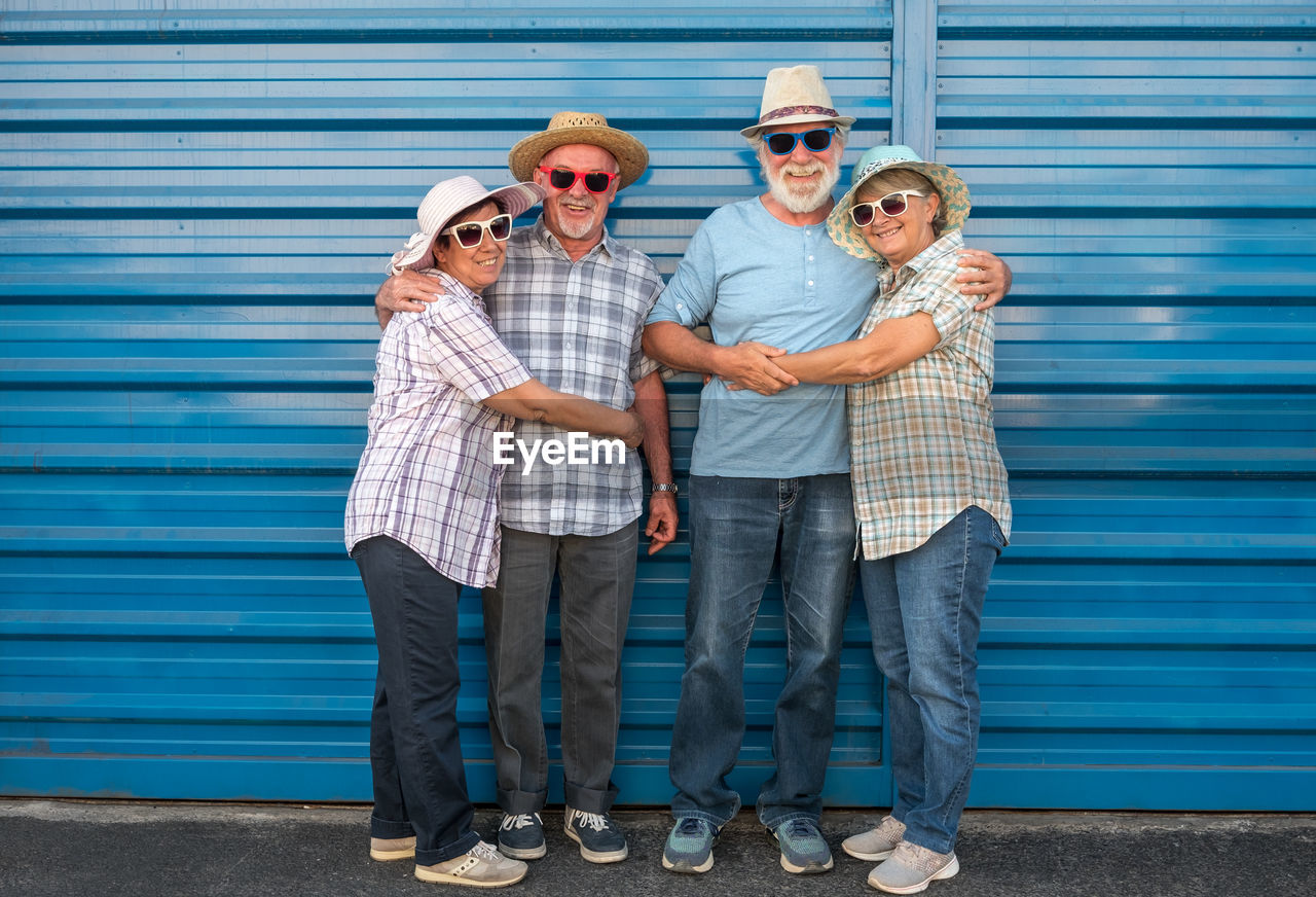 Portrait of smiling senior couples standing against shutter