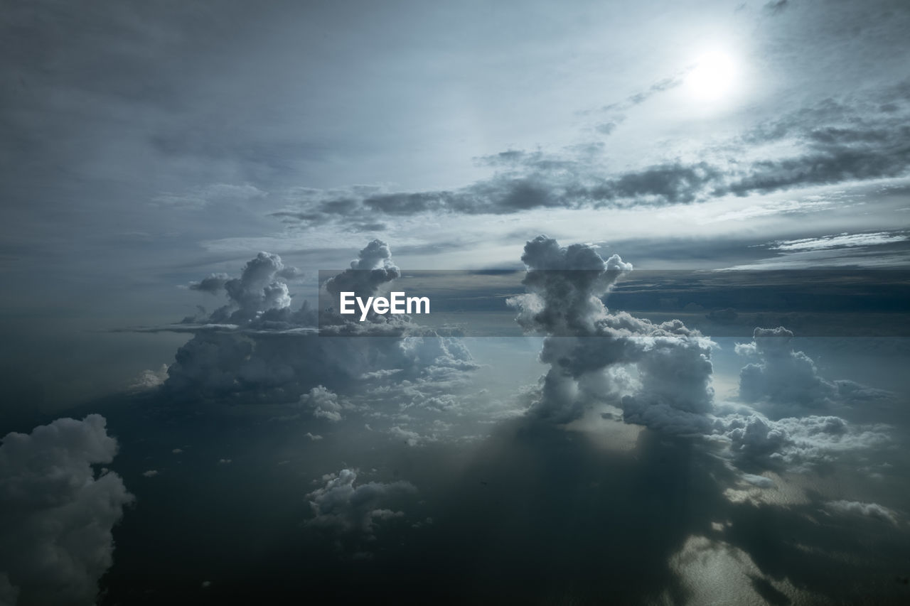 LOW ANGLE VIEW OF SUNLIGHT STREAMING THROUGH CLOUDS OVER WATER