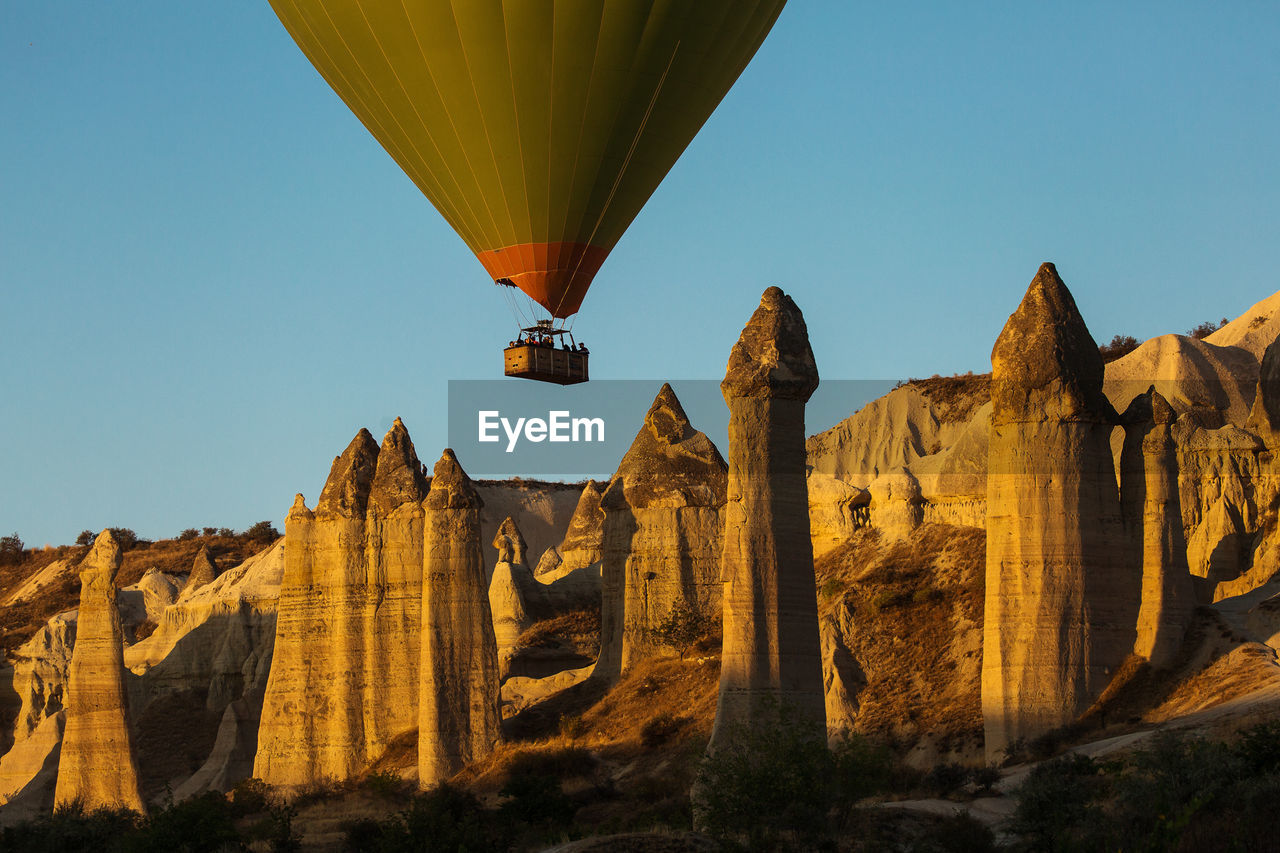 Low angle view of hot air balloon flying over rock formations