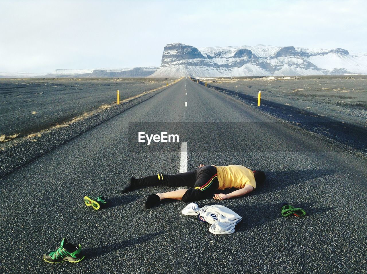 Man lying on country road along landscape