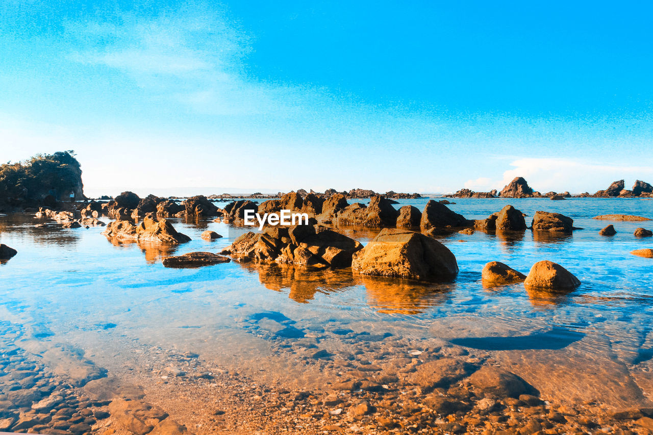 PANORAMIC SHOT OF ROCKS ON SHORE AGAINST SKY