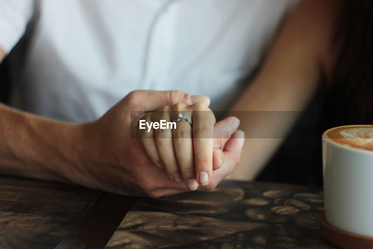 MIDSECTION OF COUPLE HOLDING HANDS