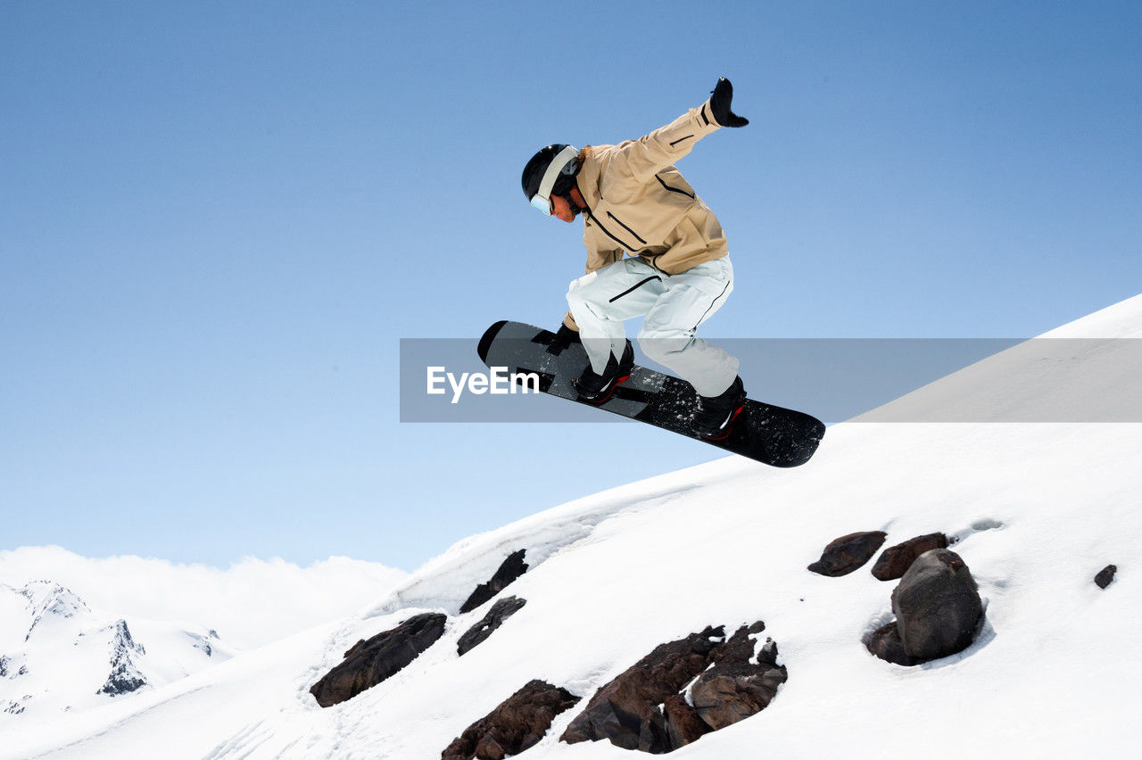 Athlete man performing tricks on snowboard, exuding confidence and control in vibrant winter gear