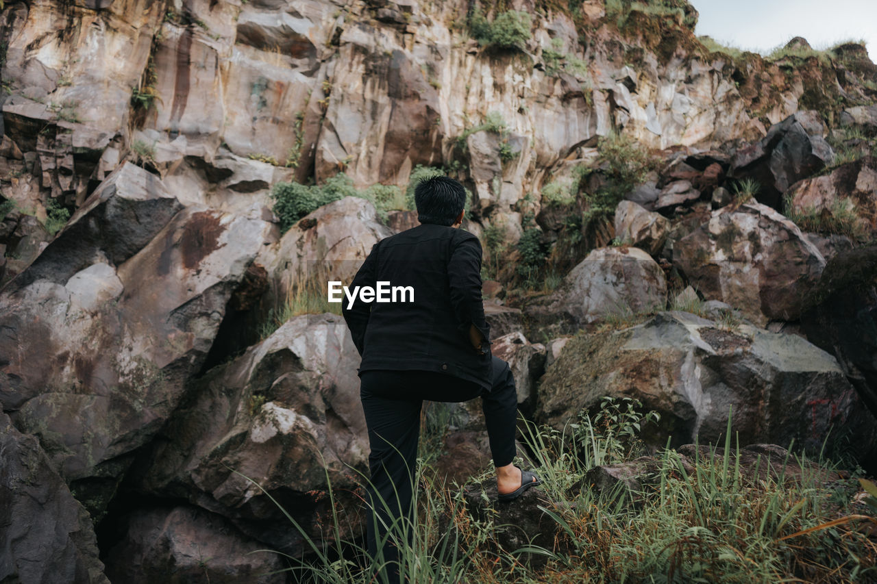 Rear view of man standing on rock formation