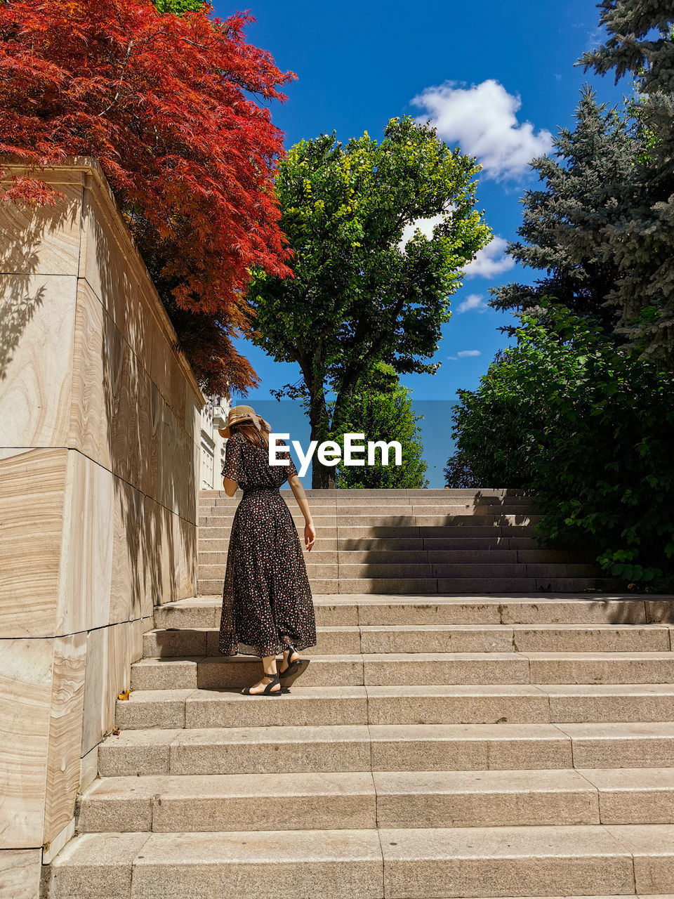 REAR VIEW OF WOMAN WALKING ON STAIRCASE AGAINST BUILDING