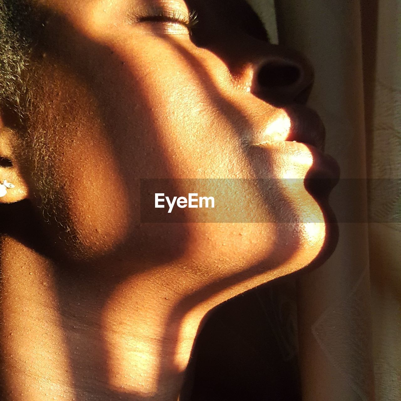 Close-up of young woman with eyes closed by window at home