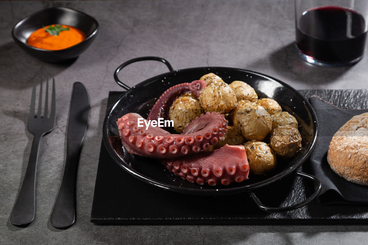 Stew octopus tentacles on skillet plate on dark table. top view.