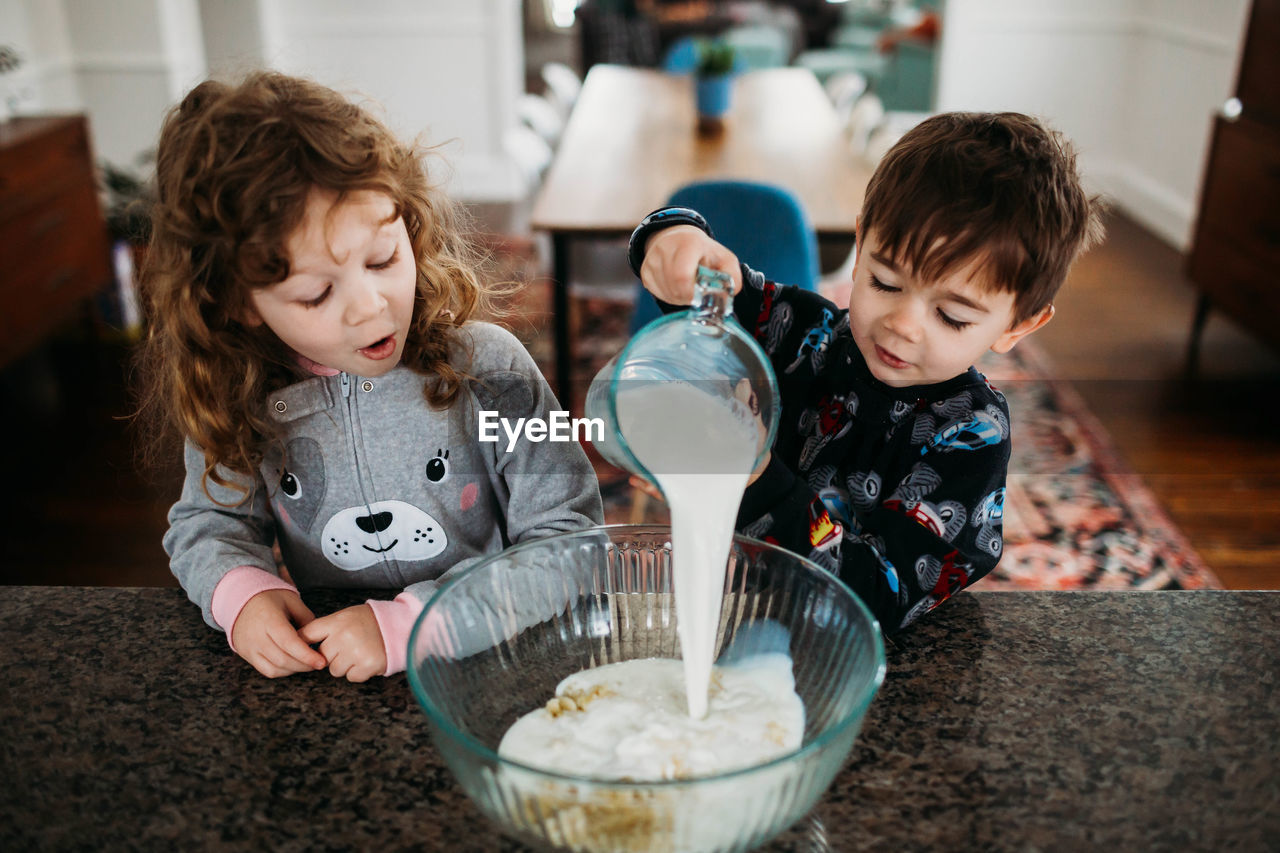 Young brother and sister wearing pjs and making creakfast together