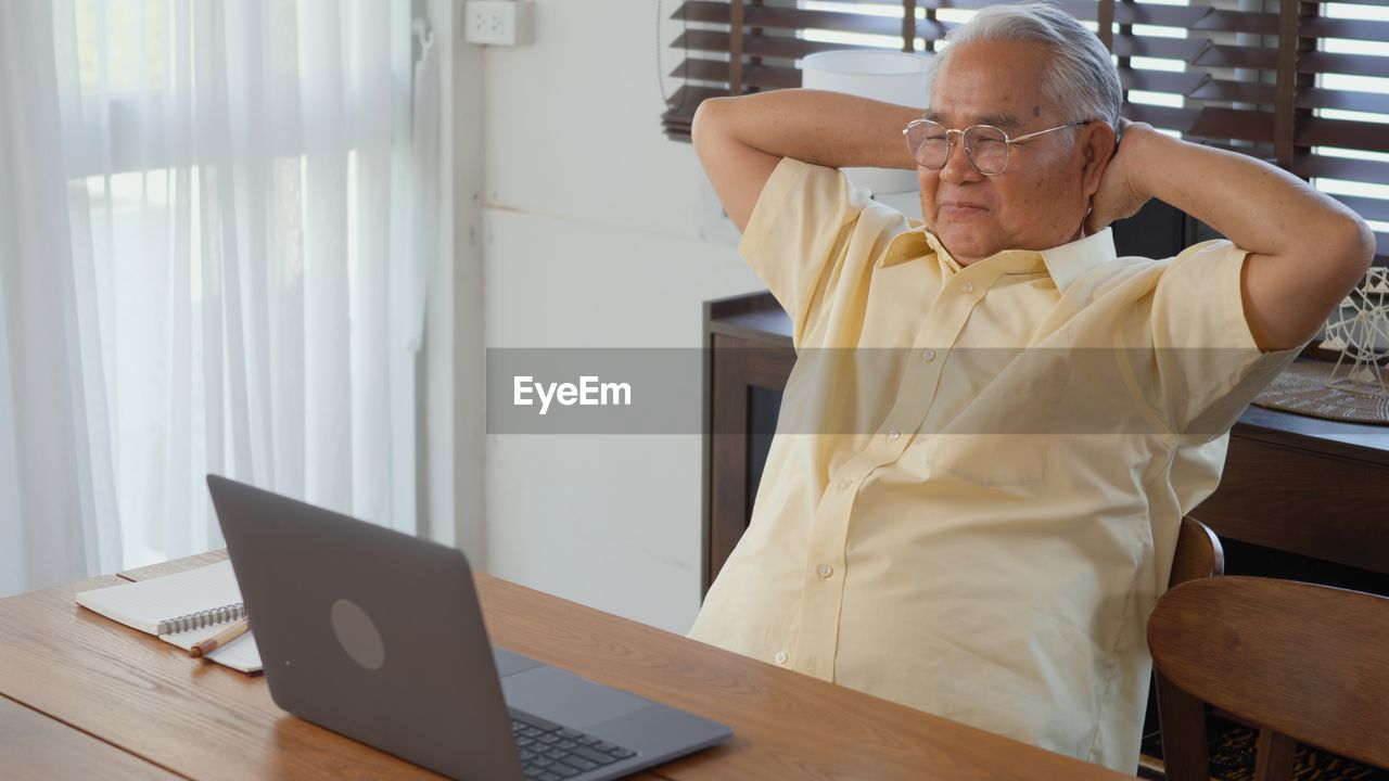 MAN USING MOBILE PHONE WHILE SITTING ON TABLE