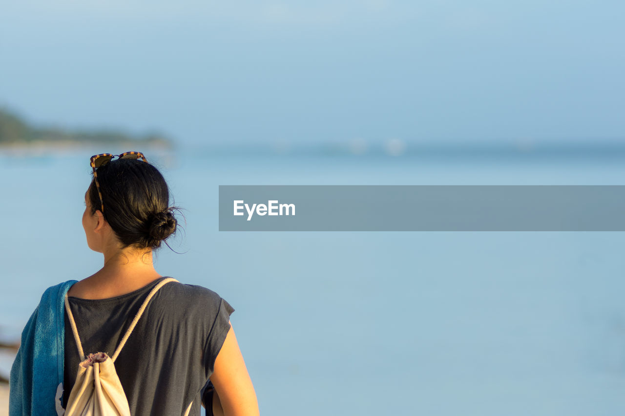 Rear view of woman at beach against sky