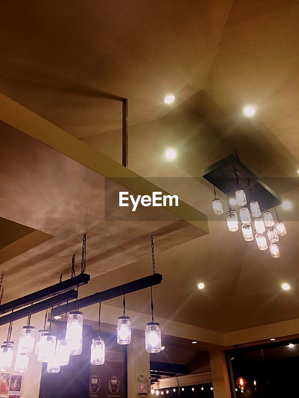 LOW ANGLE VIEW OF ILLUMINATED PENDANT LIGHTS HANGING ON CEILING