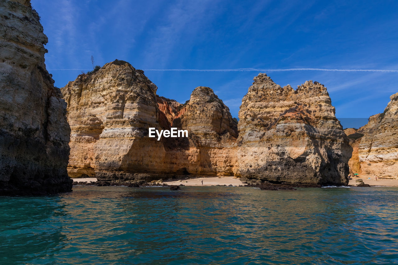 Panoramic view of rock formations in sea against blue sky
