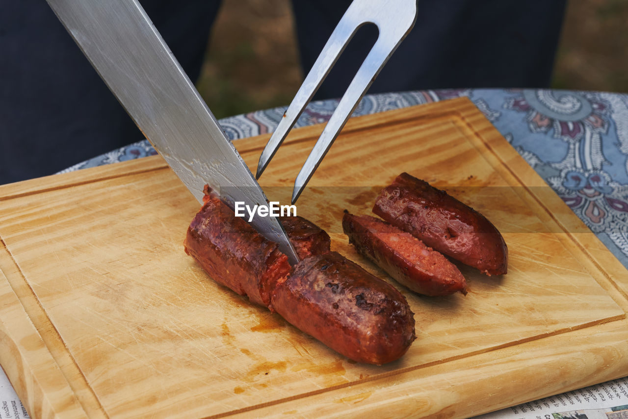 food and drink, food, meat, dish, freshness, cutting board, wood, table, high angle view, eating utensil, red meat, kitchen utensil, indoors, kitchen knife, cuisine, beef, no people, close-up, unhealthy eating, fork, meal