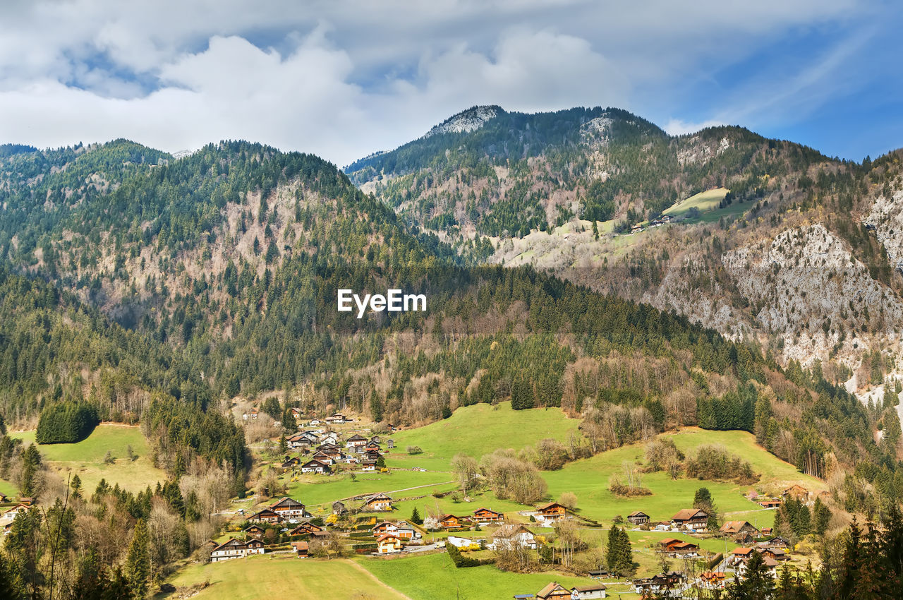 Panoramic view of townscape by mountains against sky