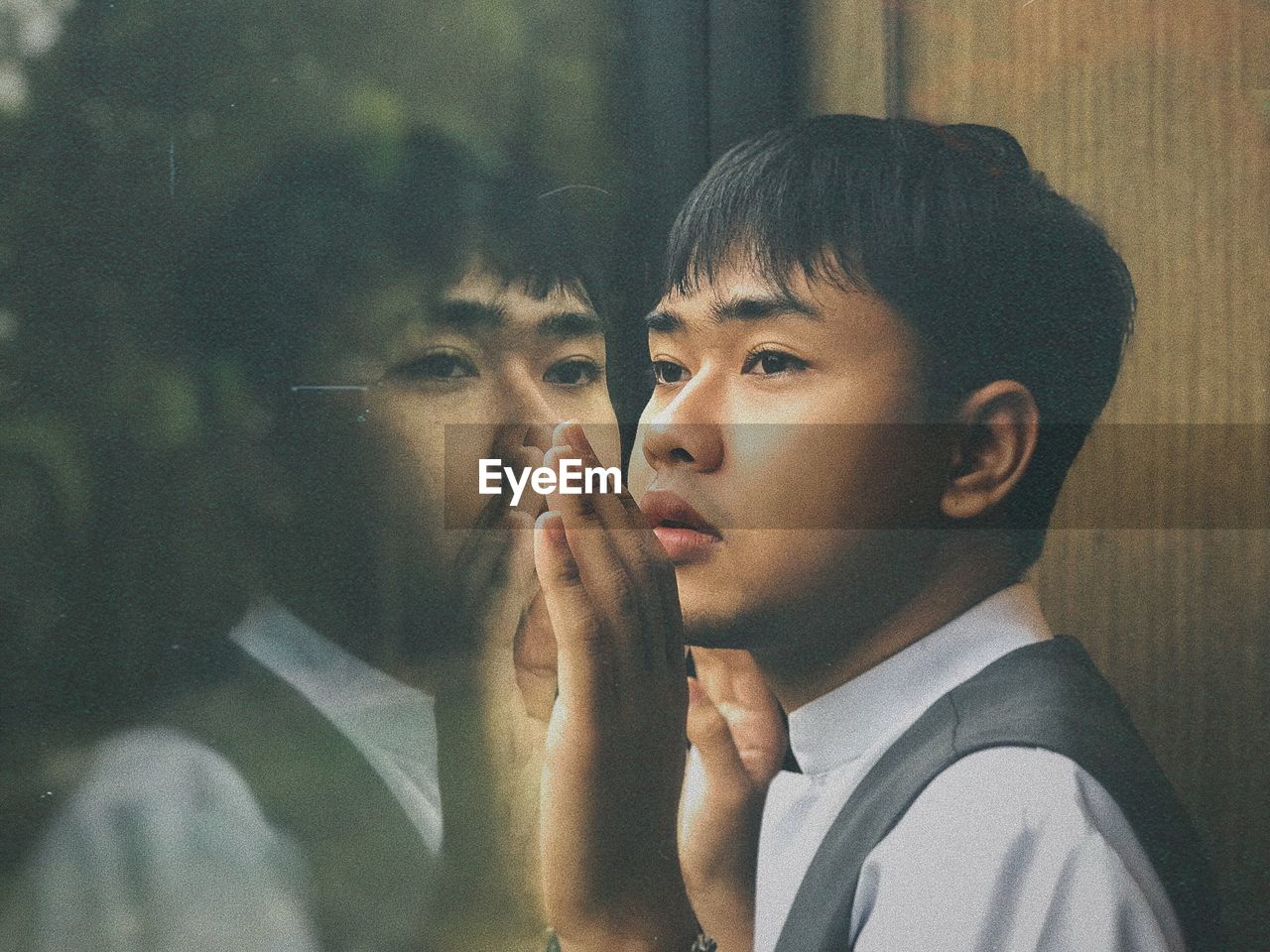 Close-up of young man looking through window