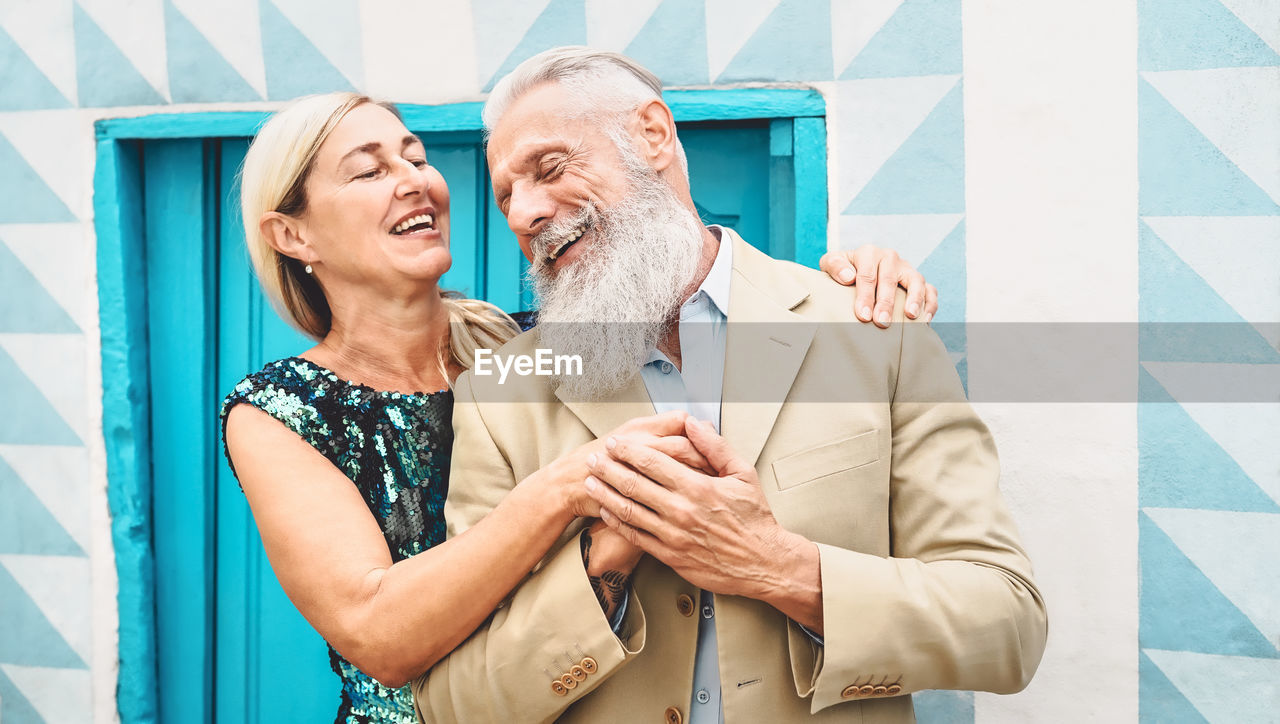 Bearded man holding woman hands while standing against wall