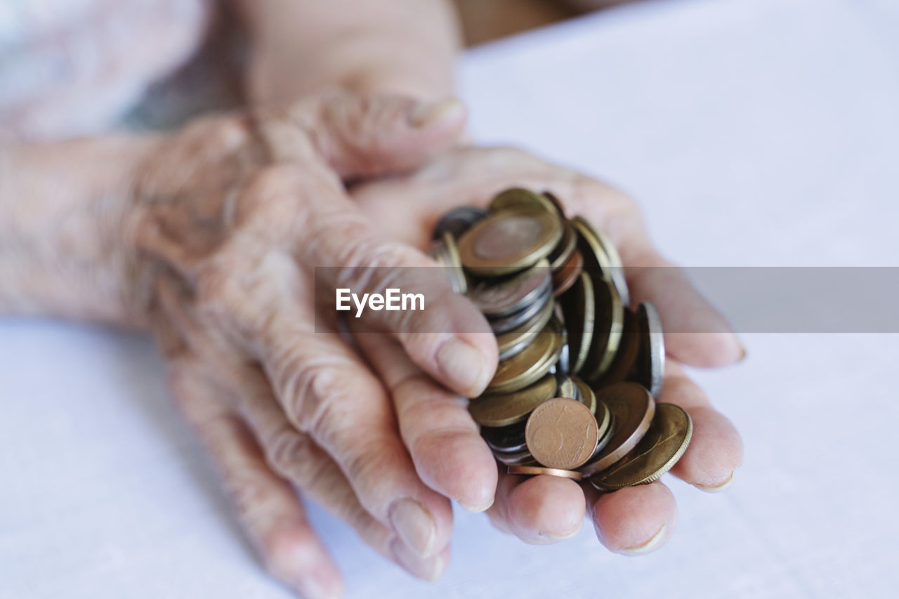 Wrinkled hands of senior woman holding coins