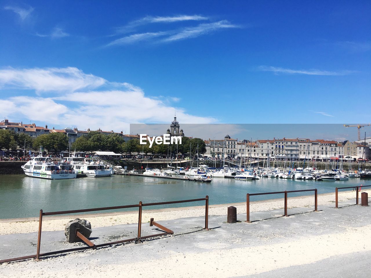 Boats moored at harbor against blue sky