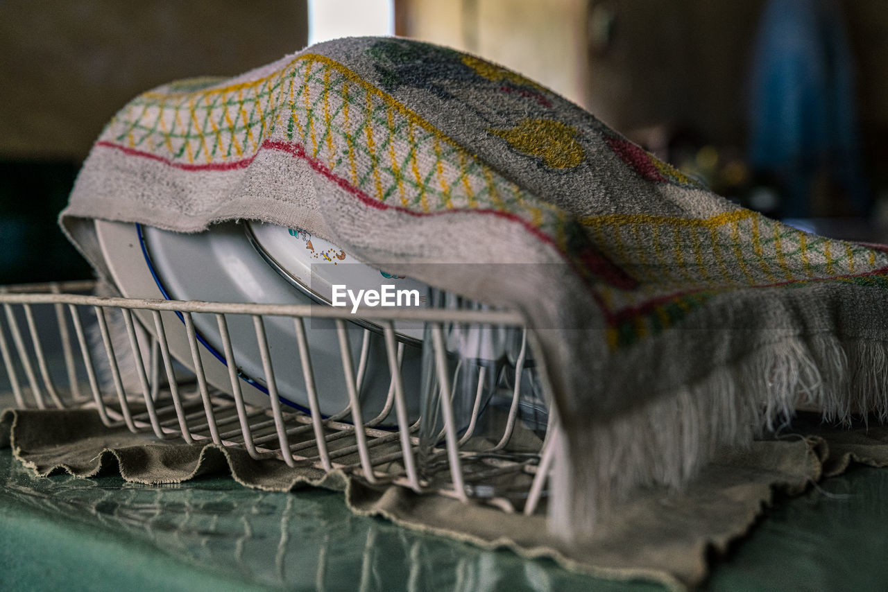 Close-up of dishes in dish rack covered by dish cloth