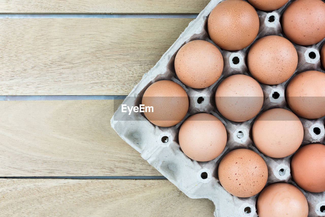 HIGH ANGLE VIEW OF EGGS IN CRATE ON WOODEN FLOOR