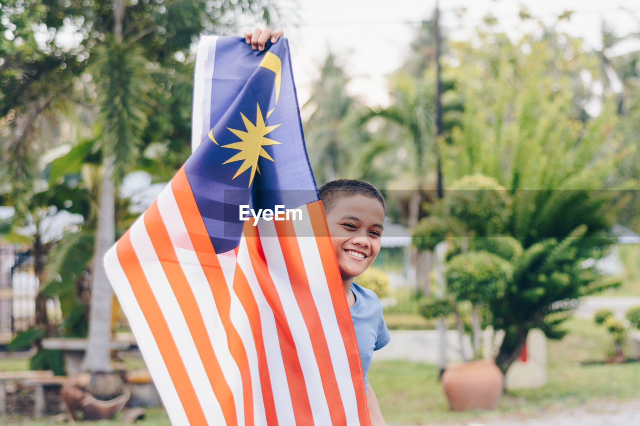 Portrait of smiling boy holding malaysian flag