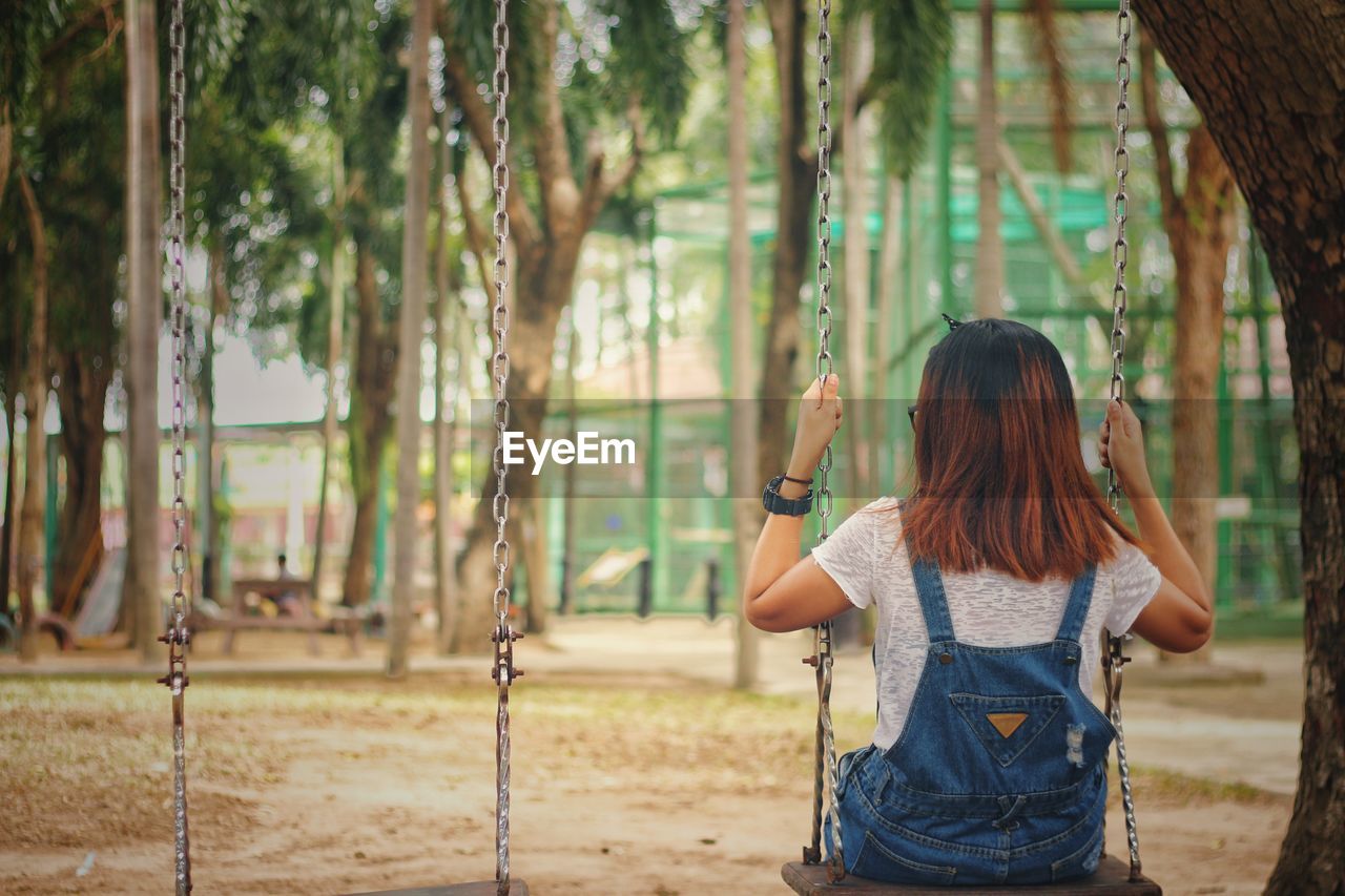 Woman sitting on swing in playground