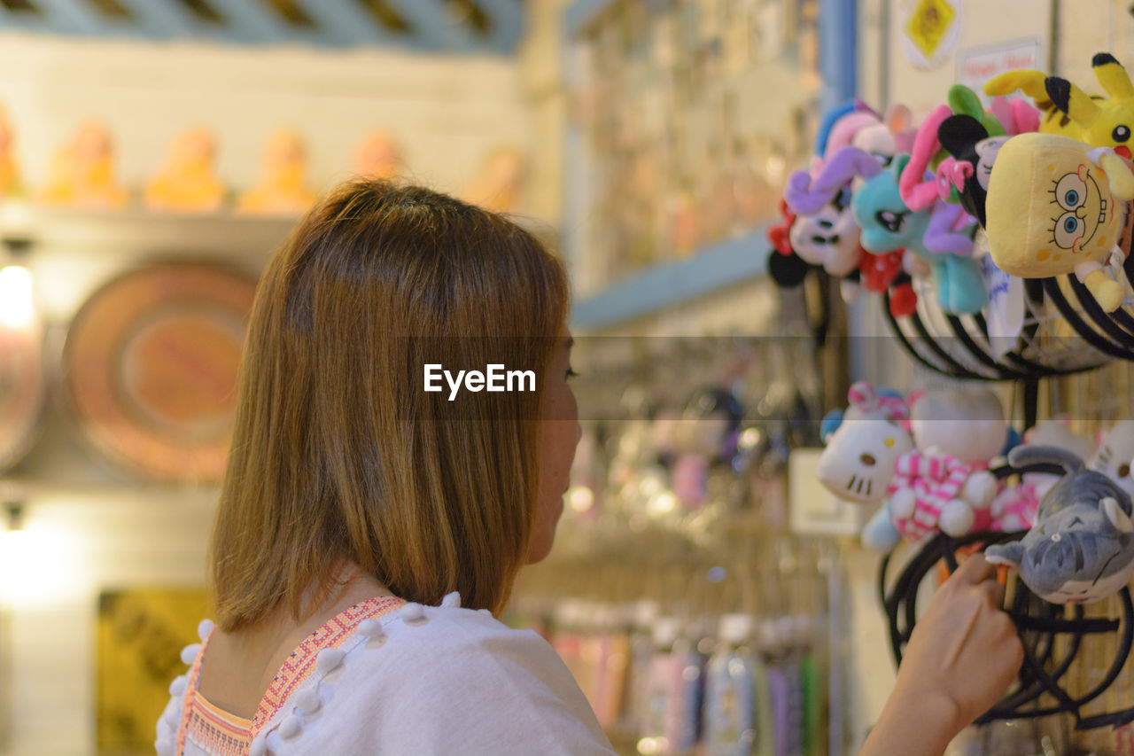 REAR VIEW OF WOMAN LOOKING AT STORE AT SHOP