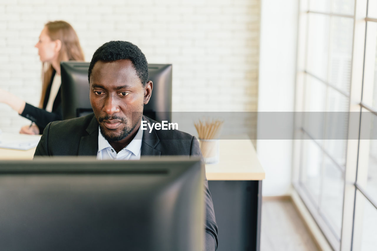 PORTRAIT OF MAN WORKING AT OFFICE