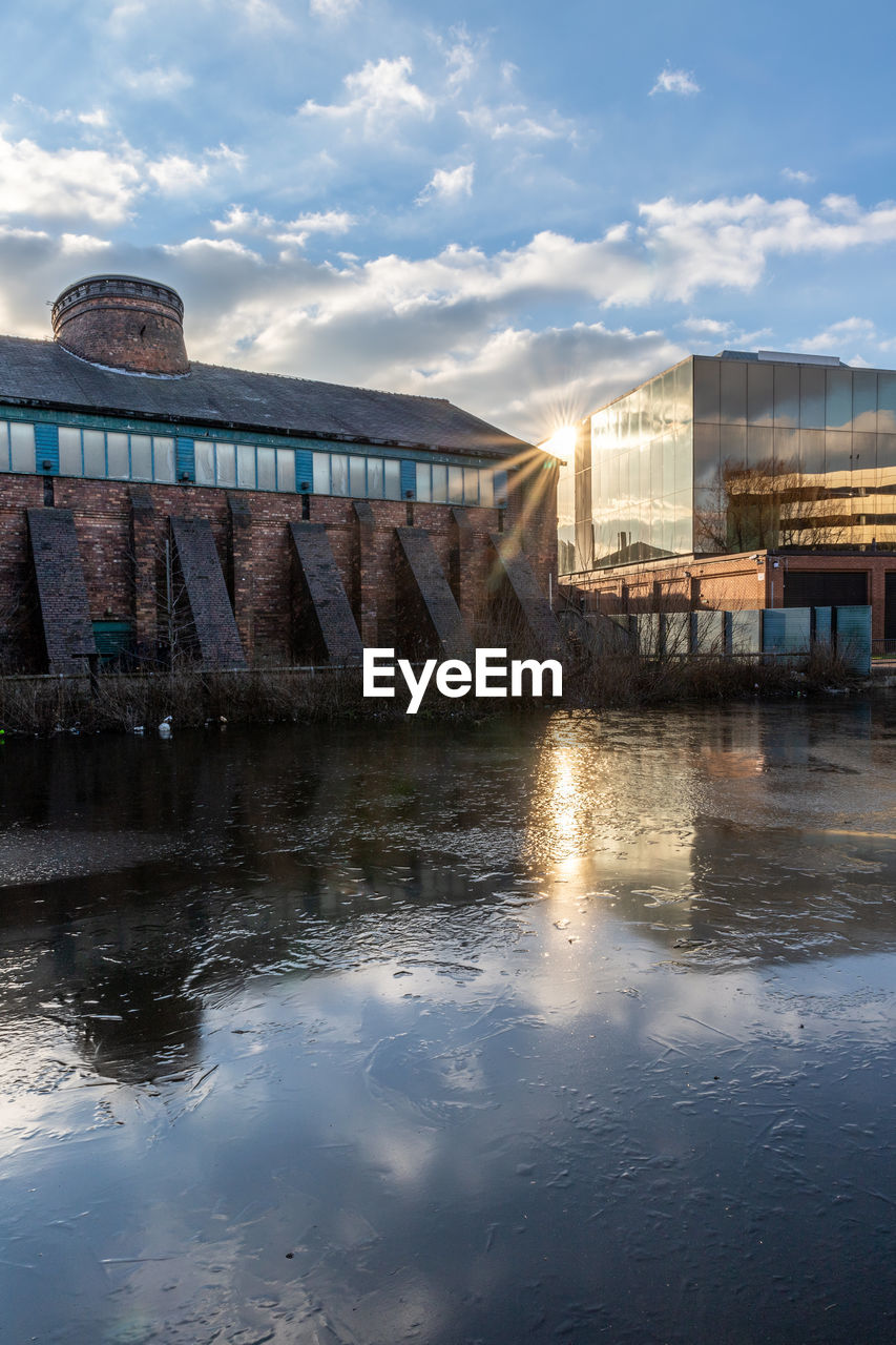 BUILDINGS BY RIVER AGAINST SKY
