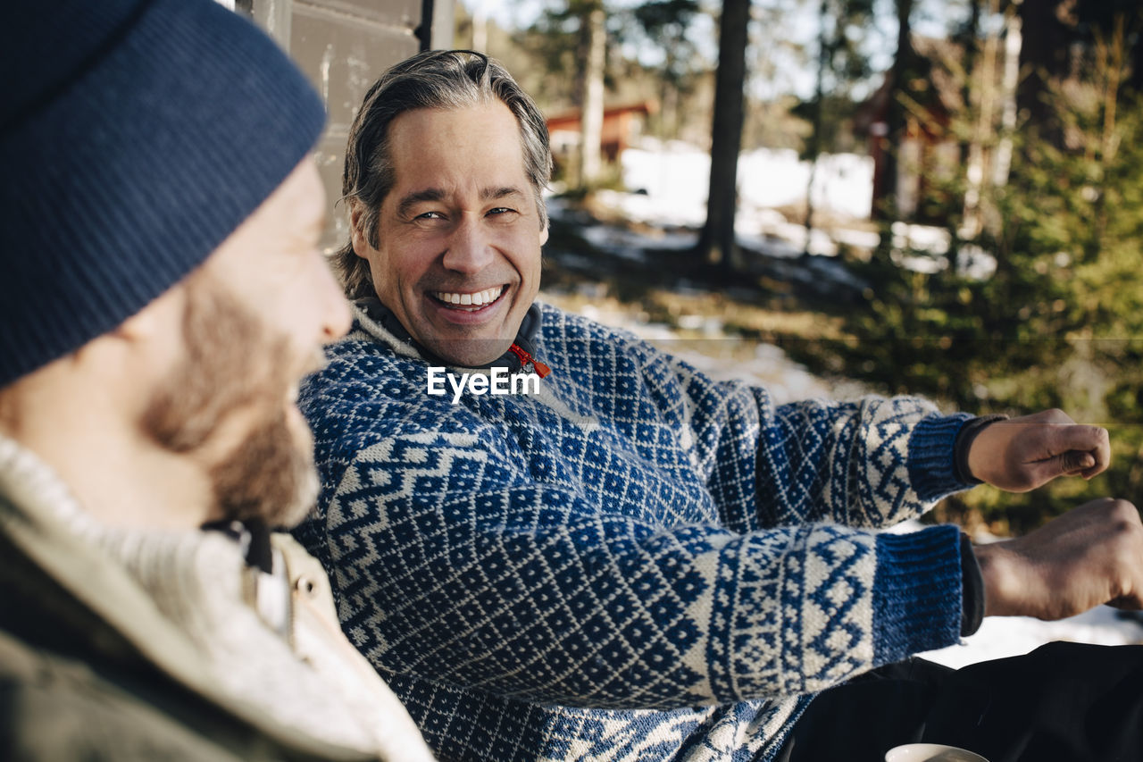 Cheerful mature man gesturing while talking with friend