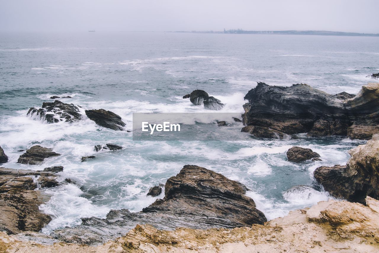 Scenic view of rocks in sea against sky