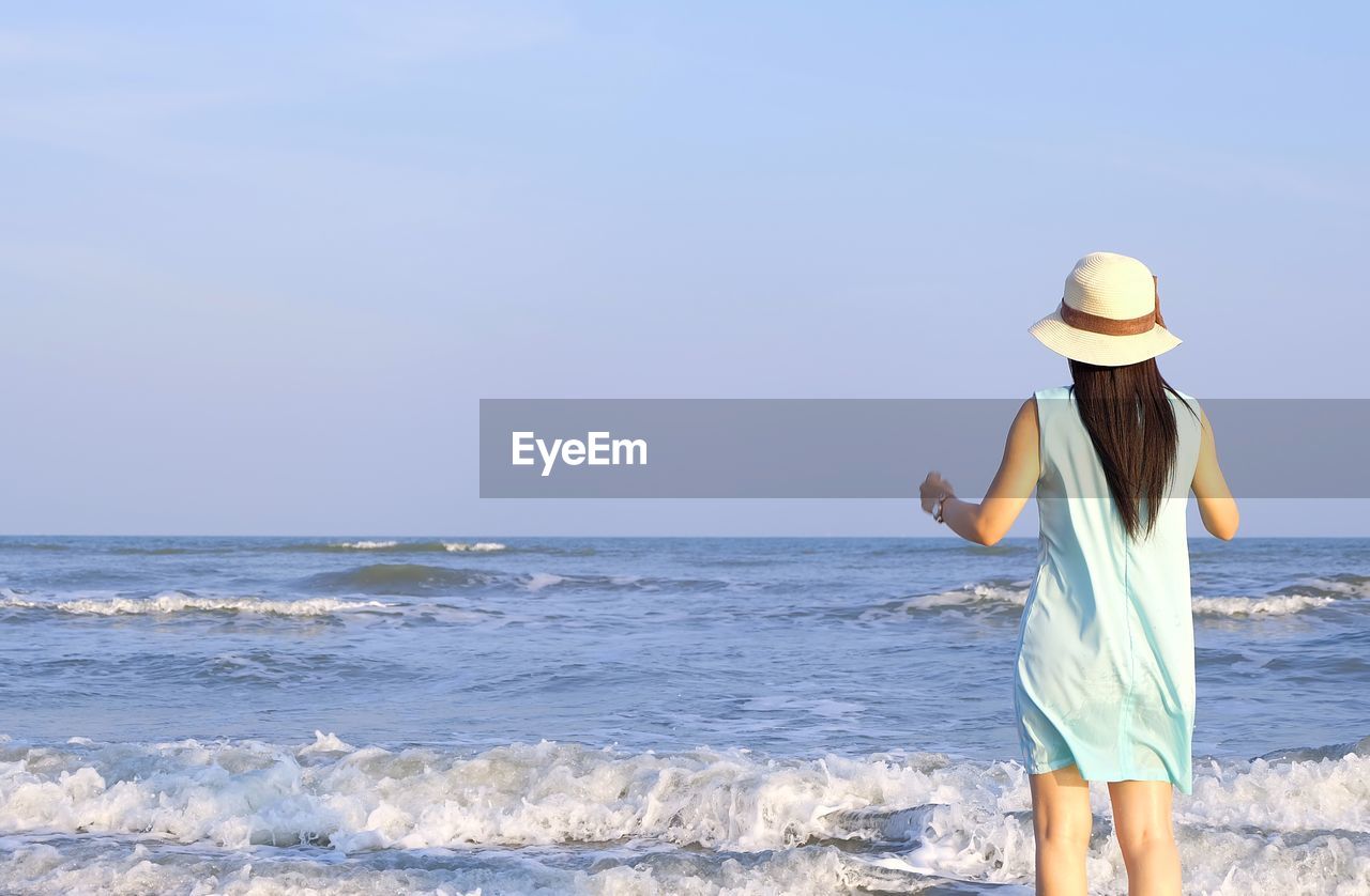 Rear view of woman looking at sea while standing against sky