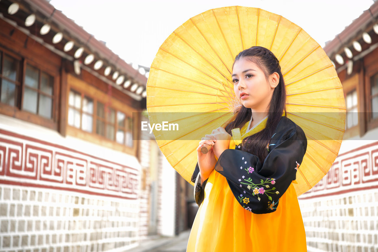 Korean girl wearing a hanbok wearing yellow umbrella. the famous palaces in seoul. 