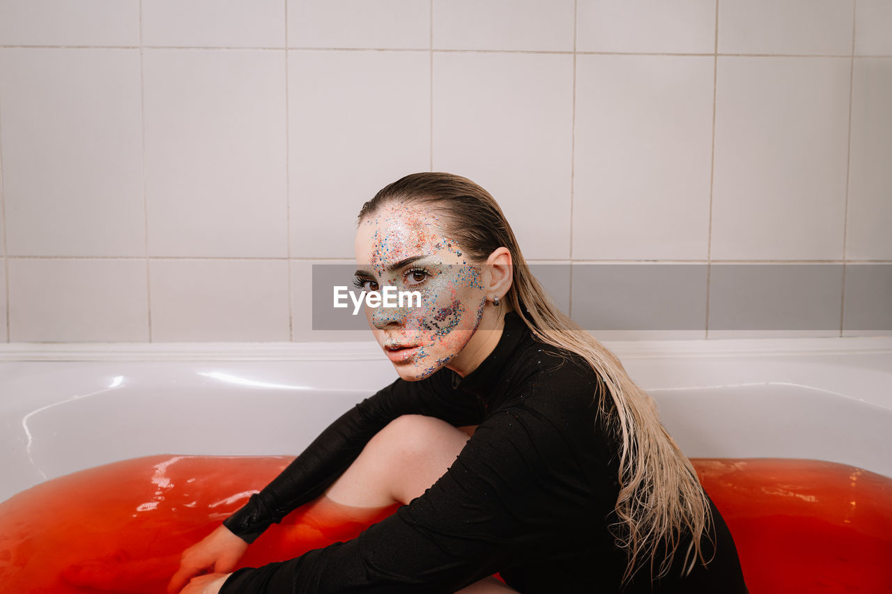 Portrait of young woman sitting in bathroom