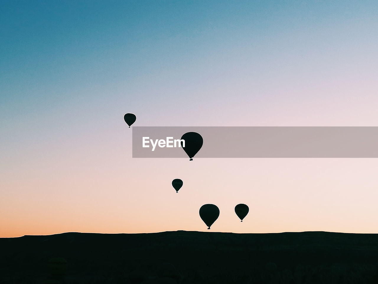 Silhouette hot air balloons against sky during sunset